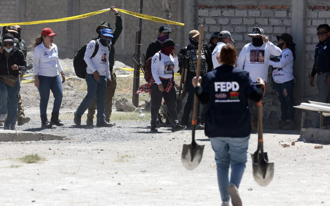 A member of the Special Prosecutor's Office for Missing Persons carries shovels, while members of the collective Guerreros Buscadores - Warrior Searchers visit the Izaguirre ranch, where on 5 March, they located three human crematory ovens while searching for their missing relatives, in a rural area of the western Mexican state of Jalisco, local authorities said on 12 March, 2025.