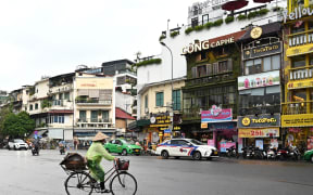 A woman rides a bicycle on the street in Hanoi on September 25, 2023 (Photo by Nhac NGUYEN / AFP)