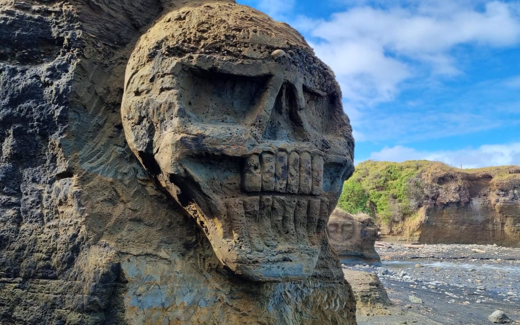 A skull carved into the sandstone cliffs at Waipipi Beach.