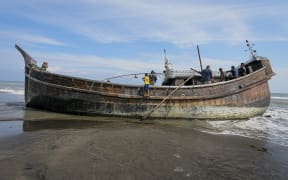 Villagers look at a wooden boat used by Rohingya people in Pidie, Aceh province on December 27, 2022. - Rohingya refugees received emergency medical treatment after a boat carrying nearly 200 people came ashore in Indonesia on December 26, authorities said, in the fourth such landing in the country in recent months. (Photo by AMANDA JUFRIAN / AFP)