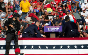 Republican candidate Donald Trump surrounded by secret service agents as he is taken off the stage at a campaign event at Butler Farm Show Inc. in Butler, Pennsylvania, 13 July, 2024.