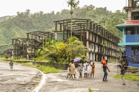 Locals walk by buildings left abandoned by a subsidiary of Rio Tinto at the Panguna mine site.