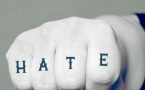 A fist with a tattoo reading 'hate'.
