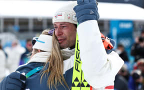 Bronze medallist Norway's Sturla Holm Laegreid is hugged following the victory ceremony of the men's biathlon 20km individual event during the 2026 Winter Olympic Games.