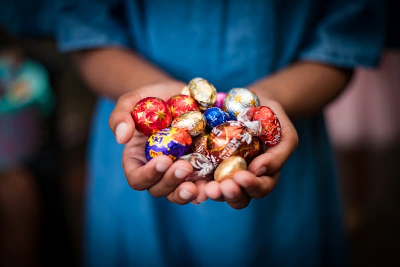 A person with cupped hands full of foil-wrapped Easter eggs.