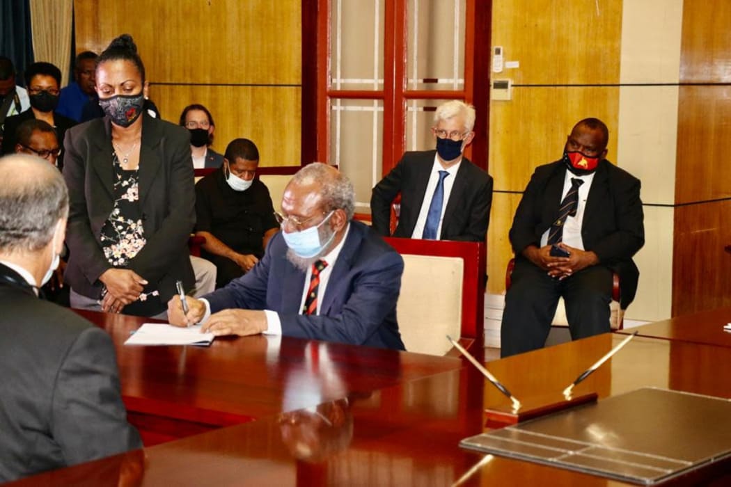 PNG's Petroleum Minister Kerenga Kua signs the Papua LNG Project Agreement with representatives of developers Total and partners ExxonMobil and Oil Search. 9 February, 2021