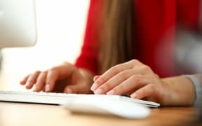 Hands of woman sitting in office and working on computer keyboard.