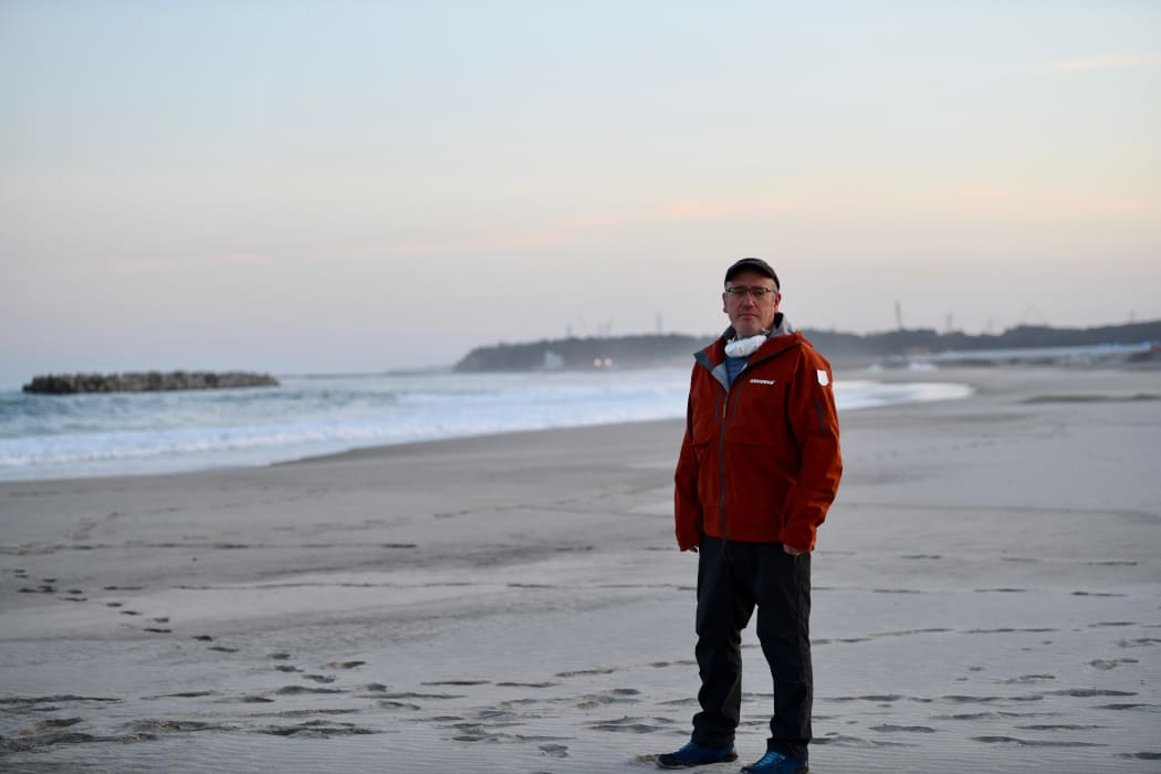 Nuclear specialist, Shaun Burnie, Greenpeace Germany, north of Fukushima Daiichi nuclear plant, with plant in background. Greenpeace.