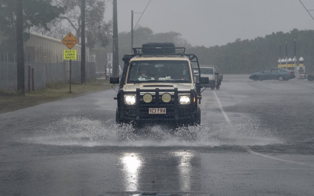A motorist drives through floodwater as Cyclone Jasper approaches landfall in Cairns in far north Queensland on December 13, 2023. A tropical cyclone was building strength as it rolled towards northeastern Australia on 13 December, with authorities warning "life-threatening" floods could swamp coastal regions for days. (Photo by Brian CASSEY / AFP)