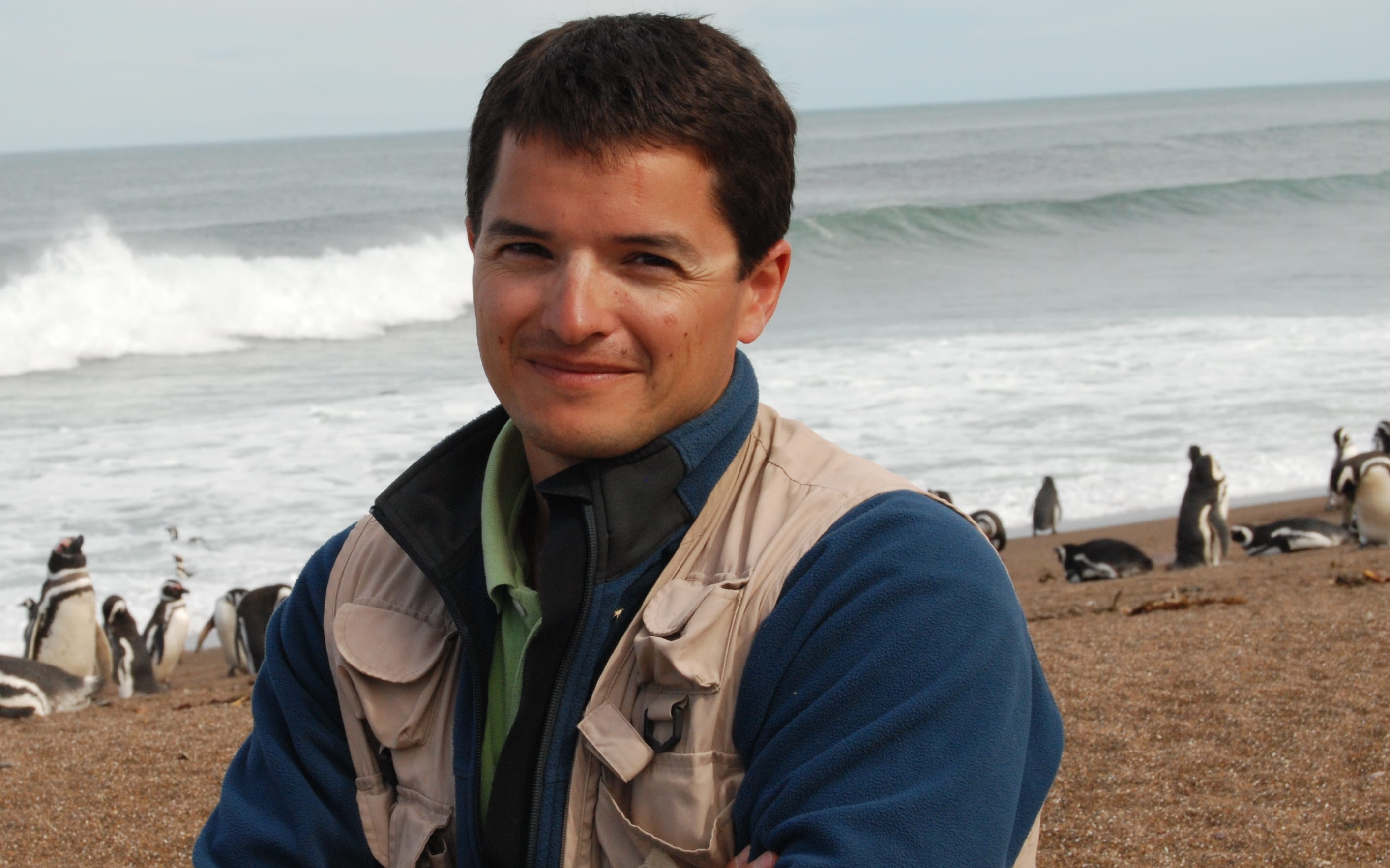 Pablo Garcia Borboroglu on a surf beach with penguins