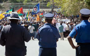 Papua New Guinea police officers watch on during a protest rally in 2013.