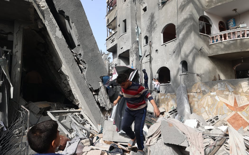 Children walk through the rubble of a destroyed building in a residential area in Deir al-Balah in the central Gaza Strip on 7 April, 2025, following overnight Israeli airstrikes.