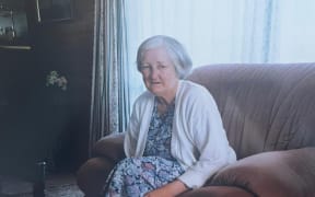 An elderly Nellie Wilson sits on the sofa