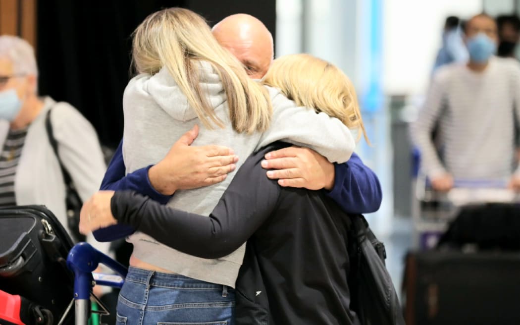 Travellers embrace at Auckland airport as vaccinated international tourists from visa-waiver countries are able to return to New Zealand, 2 May 2022.