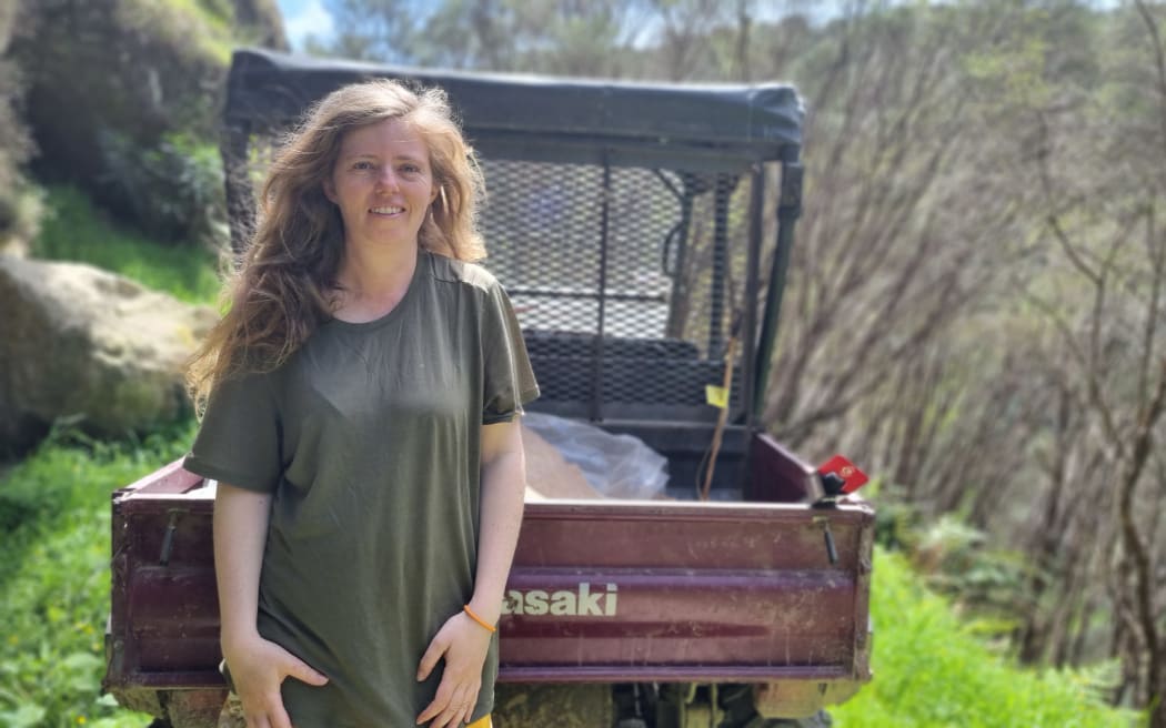 Miranda Wells against a quad bike after a drive through the 800 block where manuka are beginning to take over.