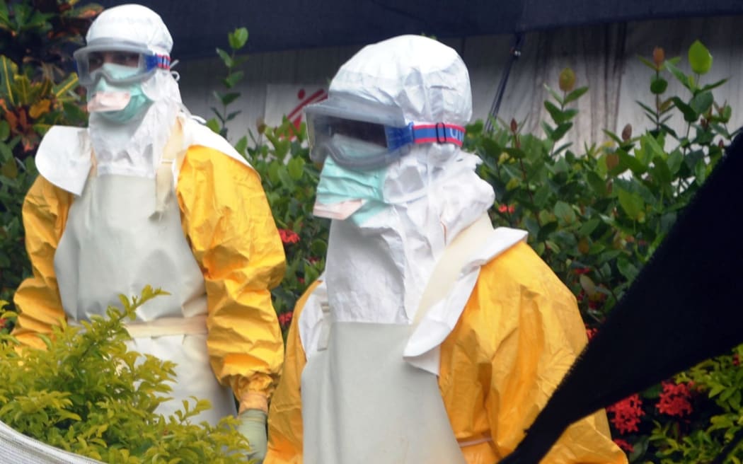 Members of Doctors Without Borders (MSF) wearing protective gear outside an Ebola isolation ward in Guinea