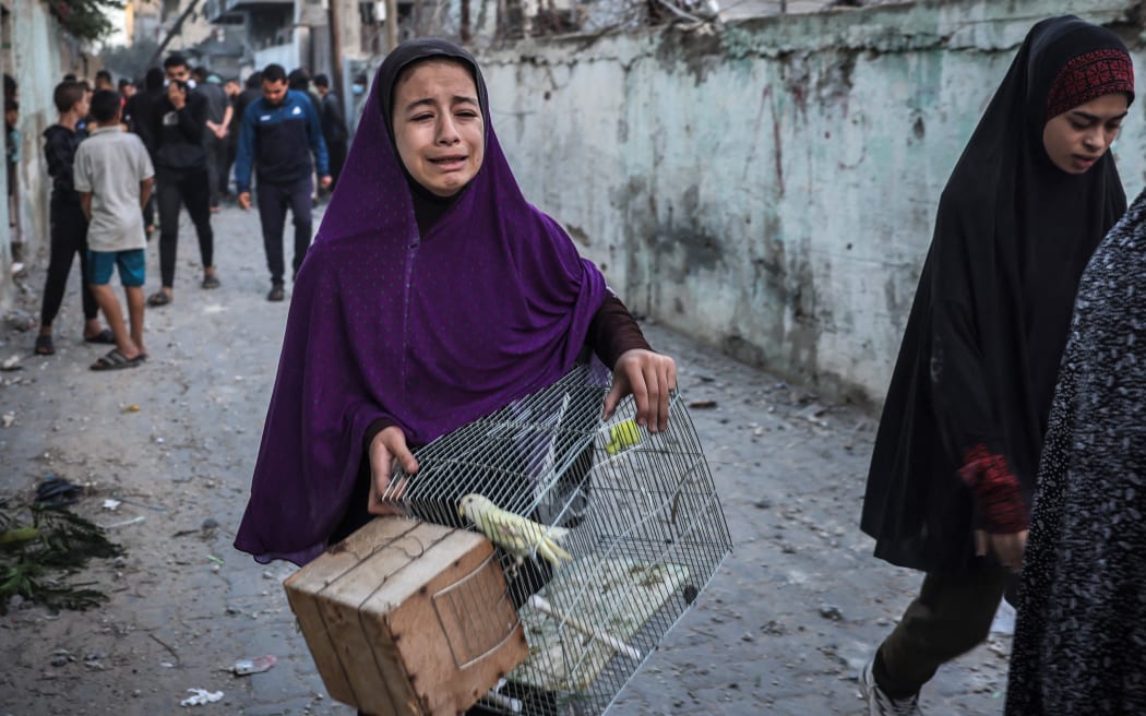A girl carrying a bird cage reacts as people flee following an Israeli strike in Rafah in the southern Gaza Strip on 23 November, 2023. (Photo by AFP)