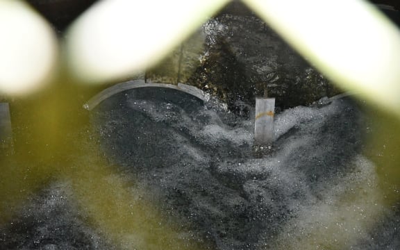 A photo of water infrastructure seen through a fence.