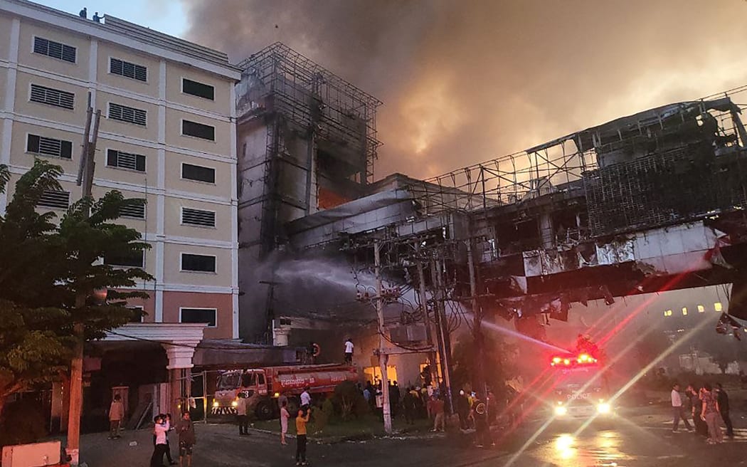 Fire-fighters spray water onto the site of a fire at the Grand Diamond City hotel-casino in Poipet on 29 December, 2022.