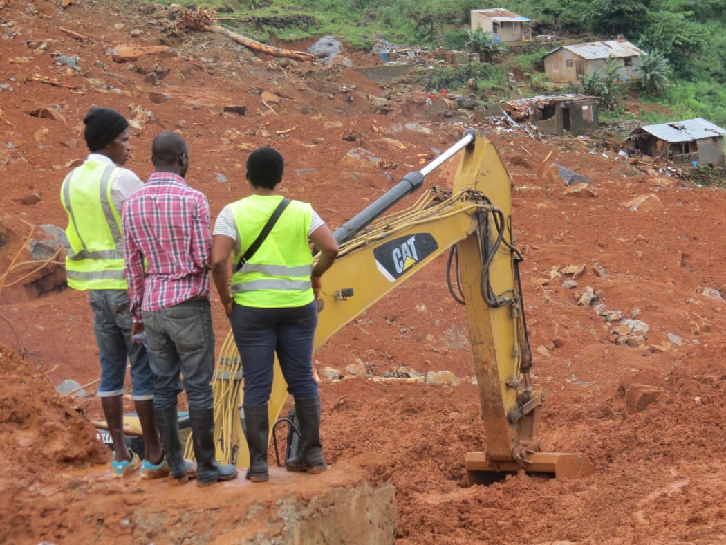 Residents watch the rescue operations at the side of a mud slide in the Sierra Leone capital Freetown on 15 August, 2017.