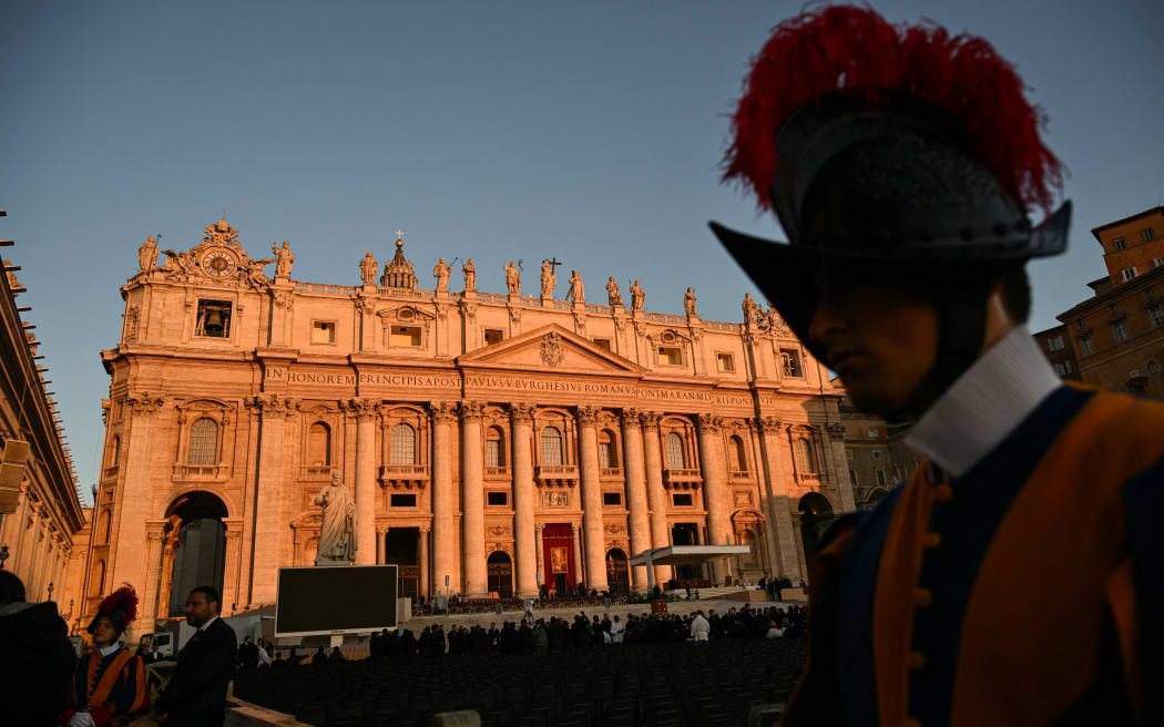 A Swiss guard stands with St Peter's Basilica in the background at St Peter's Square ahead of late Pope Francis' funeral in the Vatican on April 26, 2025. Pope Francis, champion of the poor and the Church's first Latin American leader, will be honoured April 26 with a funeral attended by world leaders and tens of thousands of Catholic faithful. The Argentine pontiff, who died on April 21, 2025, aged 88, sought to create a more open-minded Church during his 12-year papacy, and many emotional tributes have been made -- with 250,000 people paying respects at his coffin in St Peter's Basilica. (Photo by Alberto PIZZOLI / AFP)