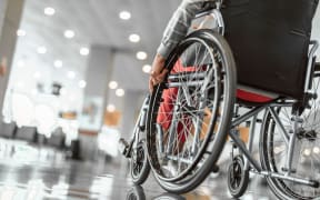 Cropped photo of mature female on wheelchair in the lobby at airport hall. Copy space in left side