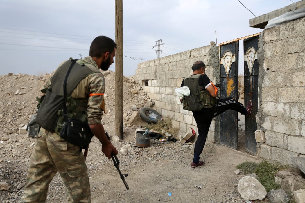 Turkey-backed Syrian fighters break open  the front door of a house at a postition that they are holding in the Syrian border town of Ras al-Ain on October 19, 2019.