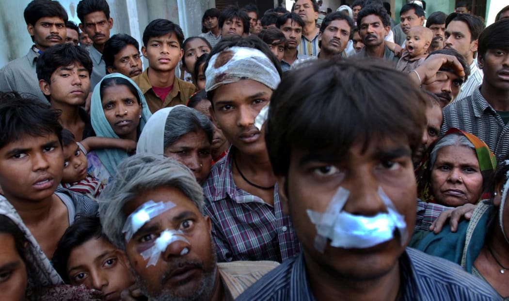 Muslims who had begged police to protect them the day before sit huddled in the wreckage of their burned out homes after a mob of Hindu neighbours attacked them from across a street.