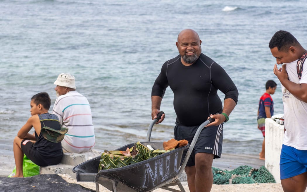 Pafelio Tumua pushing wheelbarrow of his inati.