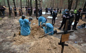 Forensic technicians dig a grave in a forest on the outskirts of Izyum, eastern Ukraine on 16 September, 2022. Ukraine said it had counted 450 graves at just one burial site near Izyum after recapturing the eastern city from Russians forces.
