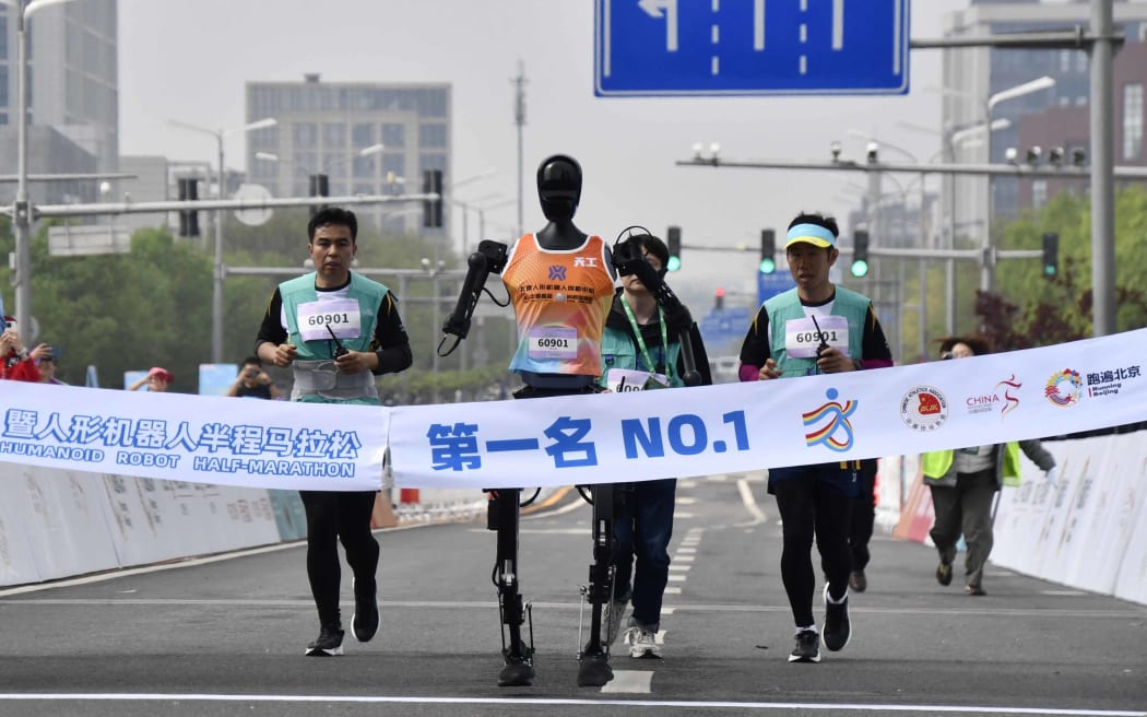 Robotic participant "Tiangong Ultra"competes as engineers run alongside during the Beijing E-Town half-marathon and humanoid robots half-marathon in Beijing.