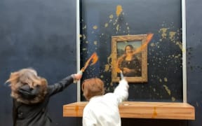 This image grab taken from AFPTV footage shows two environmental activists from the collective dubbed "Riposte Alimentaire" (Food Retaliation) hurling soup at Leonardo Da Vinci's "Mona Lisa" (La Joconde) painting, at the Louvre museum in Paris, on 28 January, 2024.