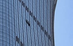 A hole is seen (R) on the side of the CITIC Tower in Beijing on June 26, 2026, after an eyewitness reported plane debris at the base of Beijing’s tallest building. Video footage taken from a nearby building by the witness showed fire trucks blasting water at smoke billowing from the 528-metre (1,732-foot) CITIC Tower, while the wreck of a plane lay on the ground beside the building. (Photo by Peter CATTERALL / AFP)