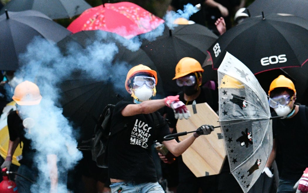 A protester throws back a round of tear gas fired by the police during a demonstration in the district of Yuen Long in Hong Kong on July 27, 2019.