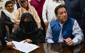 Pakistan's former Prime Minister, Imran Khan (R) along with his wife Bushra Bibi (L) looks on as he signs surety bonds for bail in various cases, at a registrar office in the High court, in Lahore on July 17, 2023.