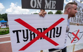 FRANKFORT, KY - AUGUST 28: A man holds a group of anti-mask and anti-tyranny signs during the Kentucky Freedom Rally at the capitol building on August 28, 2021 in Frankfort, Kentucky.