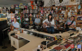 The Beths performing at Bob Boilen's desk, with the movie and music paraphernalia in the background.