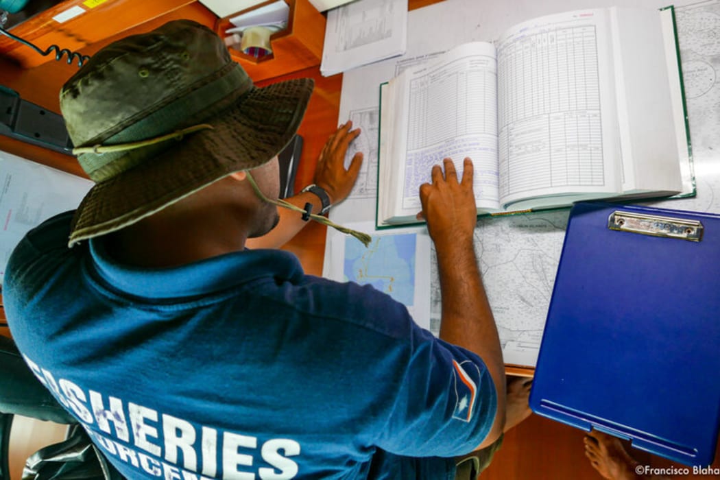 A Marshall Islands Marine Resources Authority officer crosschecks for suspicious vessel behaviours identified in the Vessel Monitoring System (map on the lower left) with Logbooks, catch logsheets, temperature records, etc. found on board.