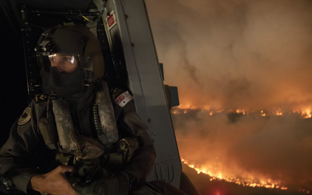This handout photo taken on December 21, 2019 and obtained on December 22 from the Australia Department of Defence shows an air crewman monitoring the Tianjara fire from a helicopter in the Moreton and Jerrawangala National Park in Moreton.