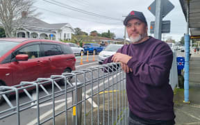 Game Changer co-owner Jai Huta leans on metal barriers installed after the failed safety upgrade of the intersection.
