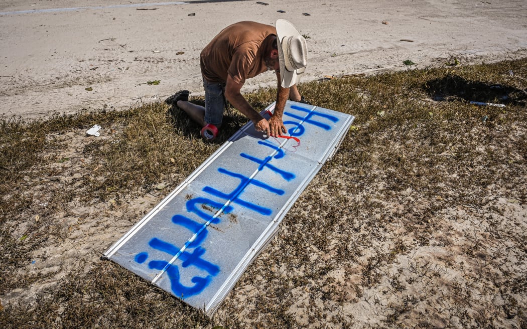 A Fort Myers Beach resident man writes "Heart Hurt?" on a piece of metal after the passage of Hurricane Ian on September 30, 2022. - Forecasters expect Hurricane Ian to cause life-threatening storm surges in the Carolinas on Friday after unleashing devastation in Florida, where it left a yet unknown number of dead in its wake. After weakening across Florida, Ian regained its Category 1 status in the Atlantic Ocean and was headed toward the Carolinas, the US National Hurricane Center said Friday. (Photo by Giorgio VIERA / AFP)