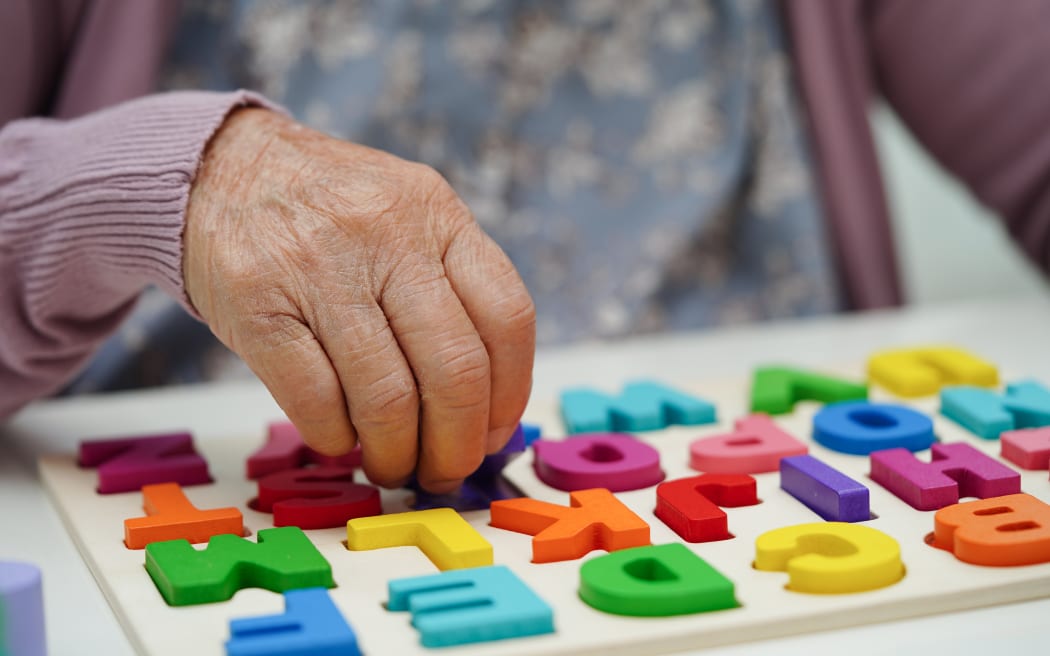 Asian elderly woman playing puzzles game to practice brain training for dementia prevention, Alzheimer disease.