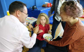 Whangarei National MP Shane Reti vaccinated 6 yr old Pippa Howie at Hikurangi School while mum Alysha looks on.