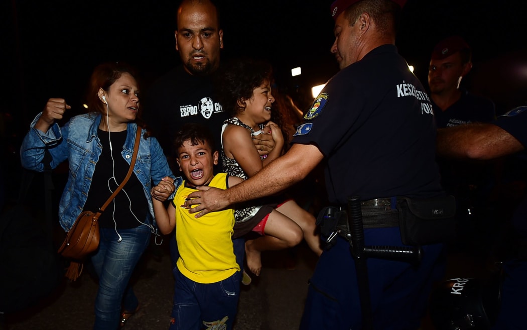 A migrant family is escorted by police from Bicske train station to a bus that will take them into a refugee camp.