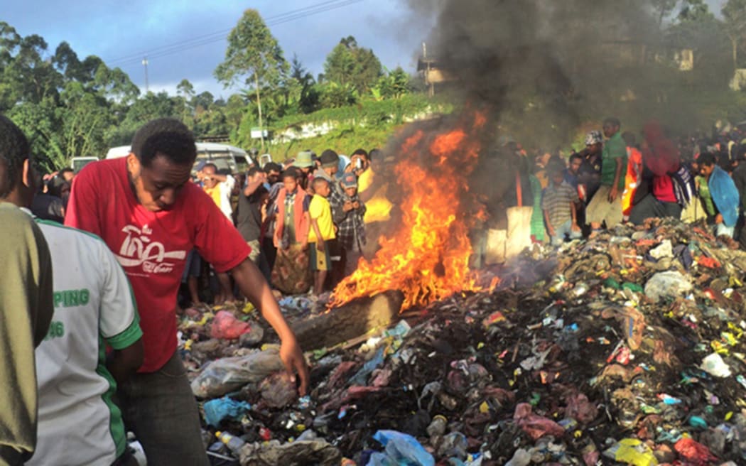 A photo taken on February 6, 2013 shows a crowd watching as a young mother accused of sorcery, is stripped naked, reportedly tortured with a branding iron, tied up, splashed with fuel and set alight on a pile of rubbish topped with car tyres, in Mount Hagen city in the Western Highlands of PNG.