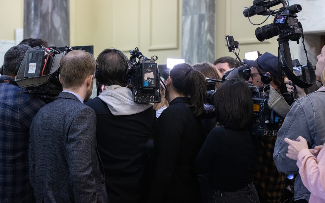 A scrum of media surrounds an MP in Parliament's Foyer.