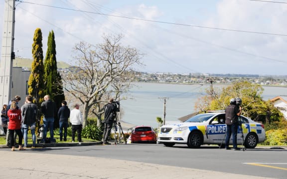 Police and onlookers at Hillsborough, Auckland, after a person in possession of a firearm was shot by police and is in a serious condition following a chase that ended on Lilac Grove.