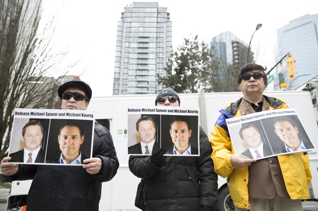 In this file photo taken on March 06, 2019 protesters hold photos of Canadians Michael Spavor and Michael Kovrig, who are being detained by China, outside British Columbia Supreme Court, in Vancouver.