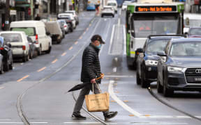 A man crosses a street in Melbourne on October 11, 2021, during a lockdown against Covid-19 coronavirus as Sydney ended a 106-day lockdown.