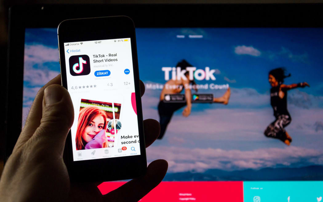 TikTok mobile video-sharing app company logo on phone screen with internet homepage in background.